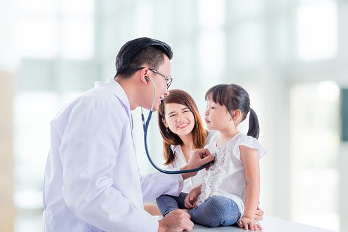 Asian doctor examining a girl by stethoscope ,mother standing beside her daughter at hospital