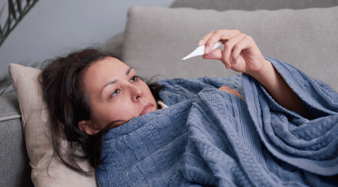 Người bị sốt kèm cảm giác ớn lạnh đang nằm nghỉ và giữ ấm cơ thể bằng chăn.