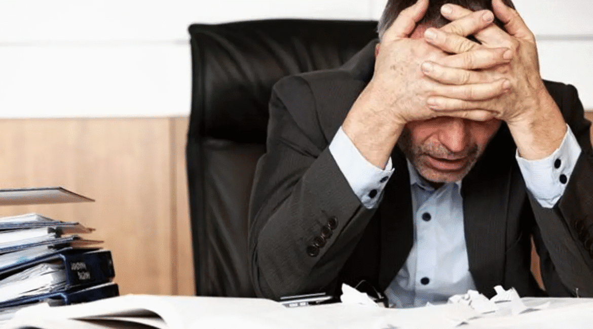 Người căng thẳng ôm đầu tại bàn làm việc, biểu hiện stress trong cuộc sống hiện đại