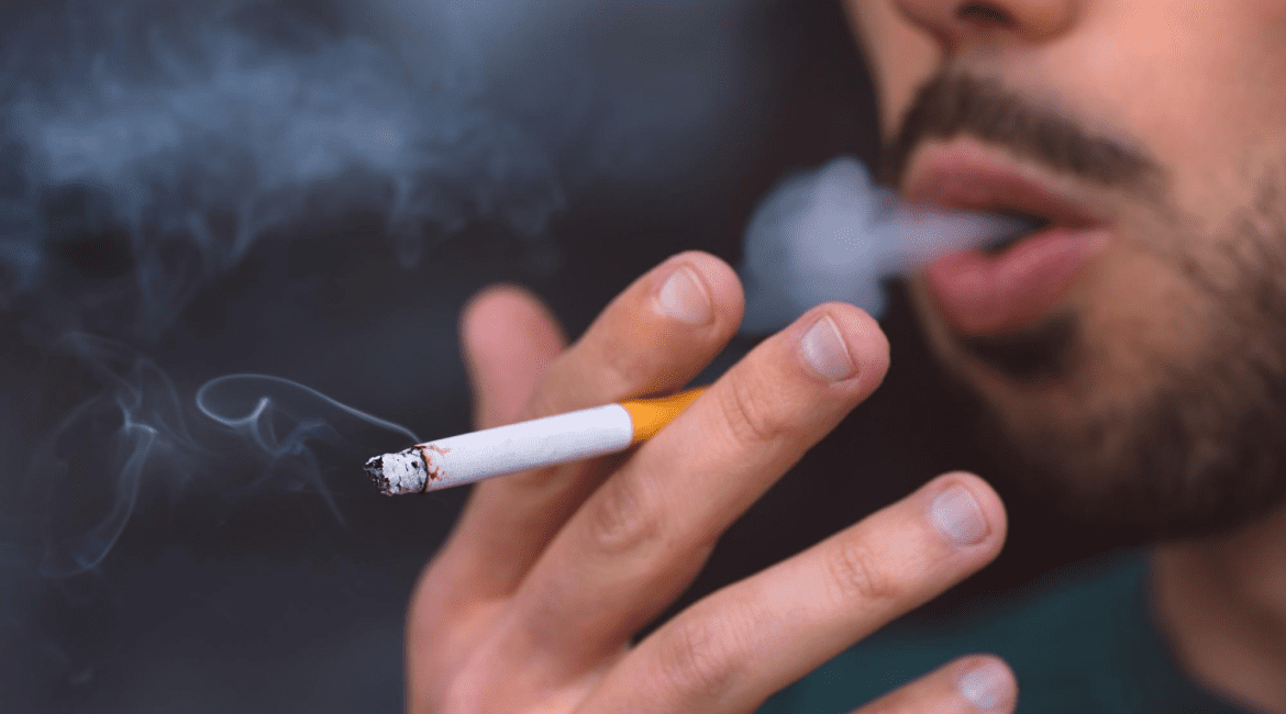 Người đàn ông đang hút thuốc lá với làn khói thuốc bao quanh khuôn mặt.